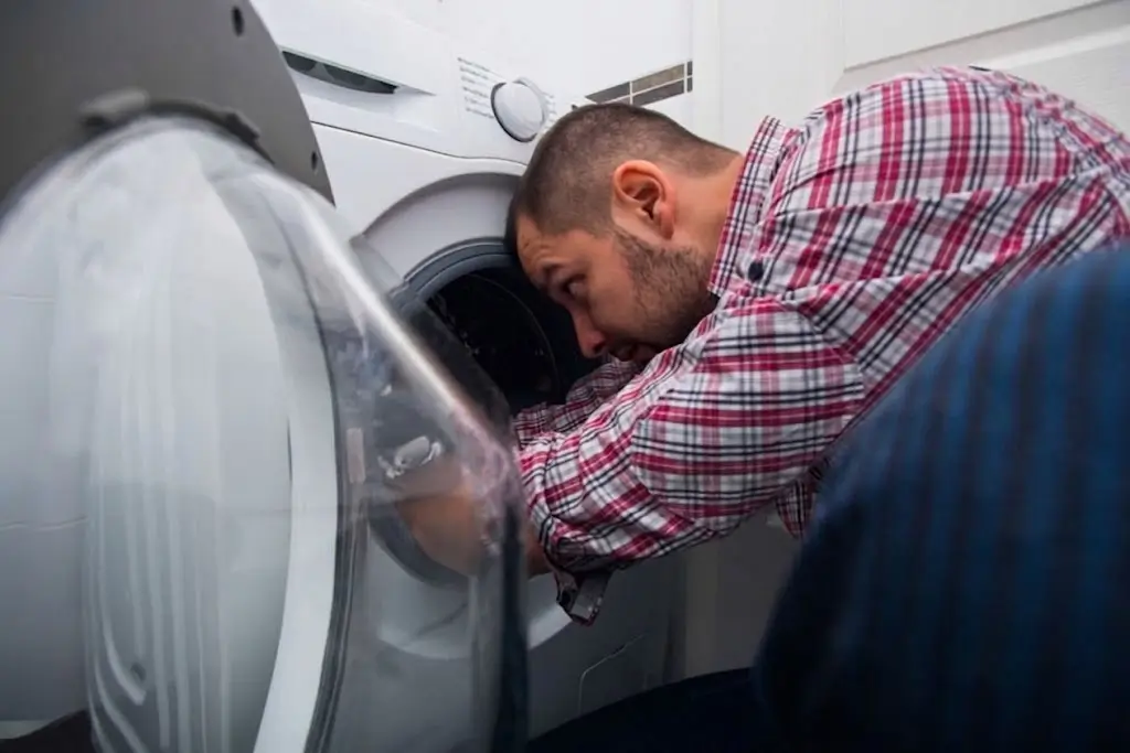 A Fasteny Appliance Repair technician providing expert service, inspecting a front-loading dryer for repair.