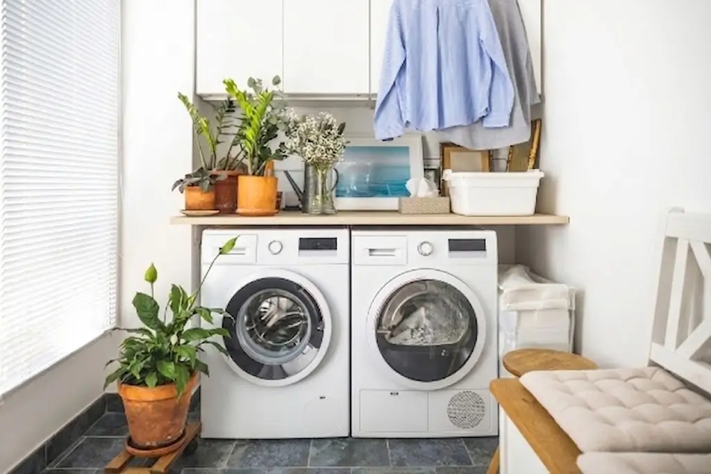 A bright, organized laundry room setup featuring a modern front-loading washing machine and dryer side-by-side.