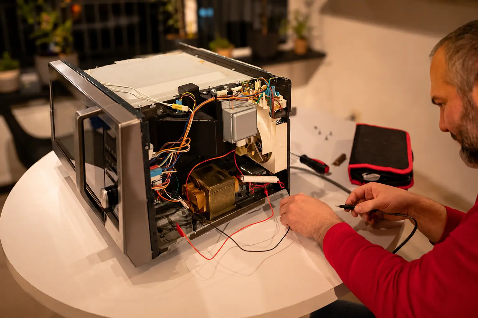 Professional microwave repair service technician diagnosing and repairing an open microwave unit.