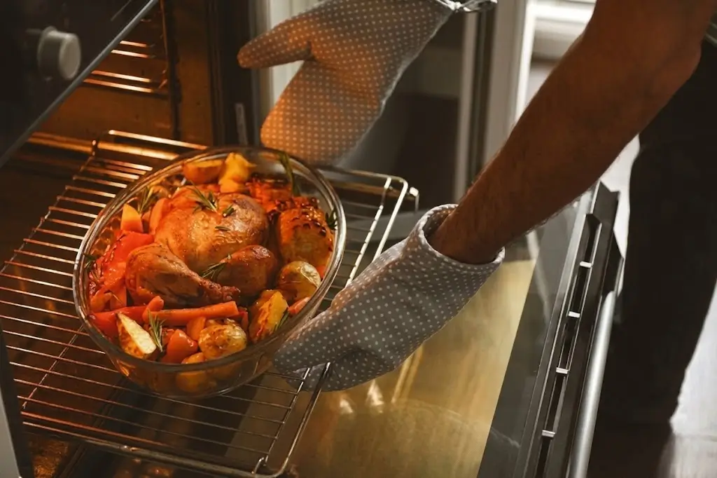 A homeowner pulls a freshly roasted chicken from a smoothly operating oven, after a successful oven repair service.