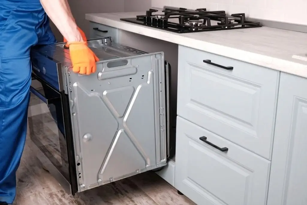 A Fasteny Appliance technician assembling and installing a built-in kitchen oven into a cabinet opening.