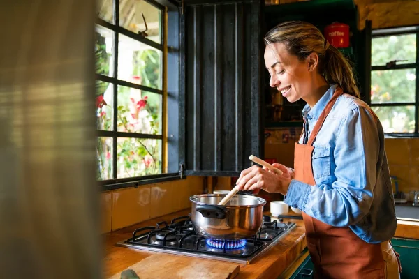 Woman cooking on a cooktop with visible burner flames.